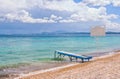 View of the beach Ã¢â¬â turquoise water, golden colored pebbles and small wooden berth Royalty Free Stock Photo